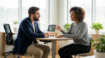 Un homme et une femme discutant sérieusement et avec bienveillance dans un bureau lumineux.